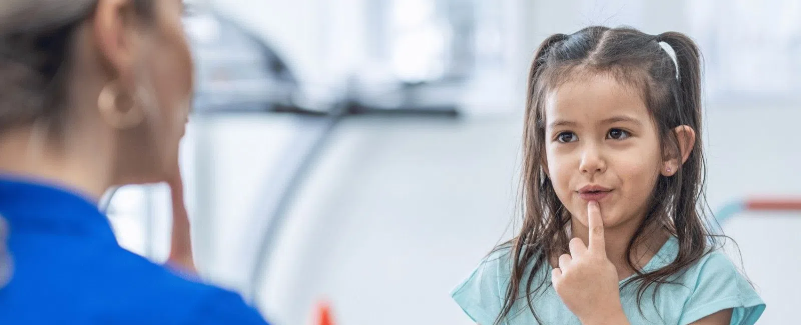 Young girl engaging with a therapist using colorful stacking toys in a bright therapy room.