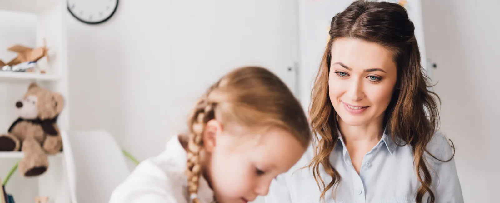 A mother helping her daughter with homework at a bright, organized study space.