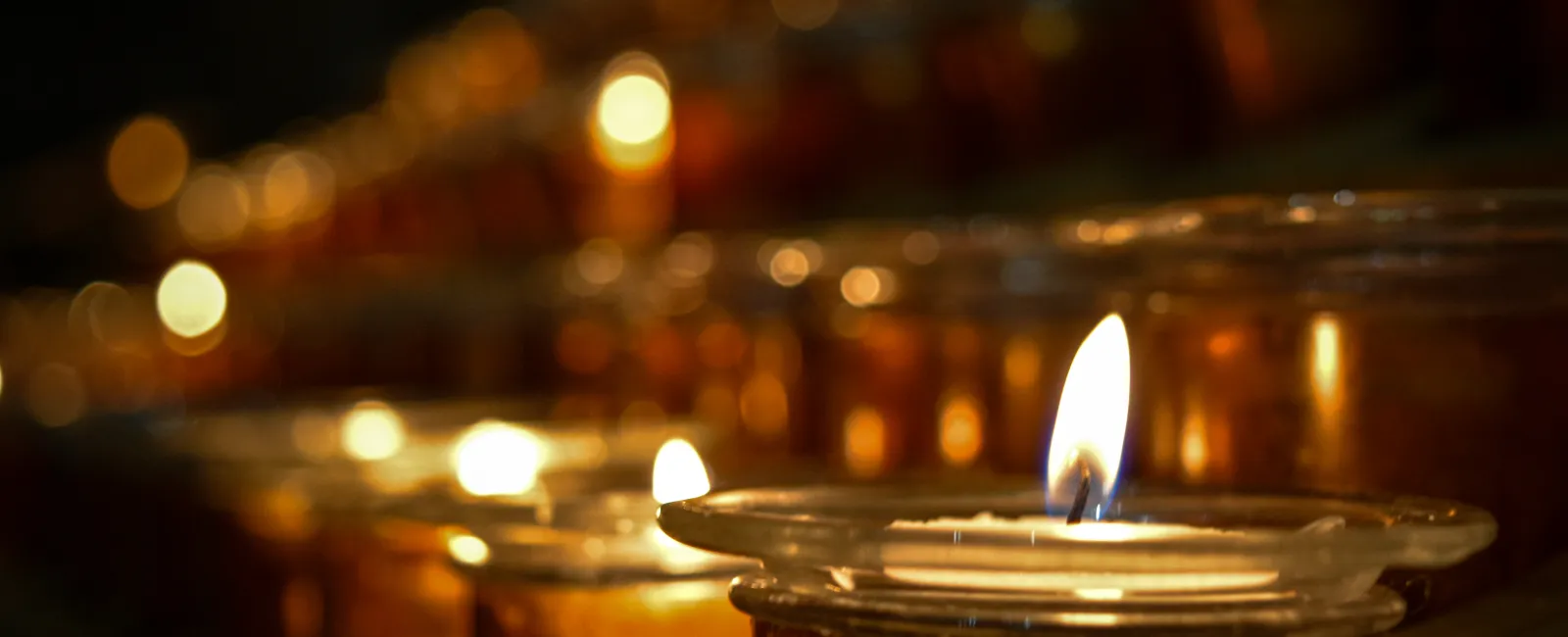 Close-up of glowing candles in glass holders creating a warm, serene atmosphere with soft bokeh lights.