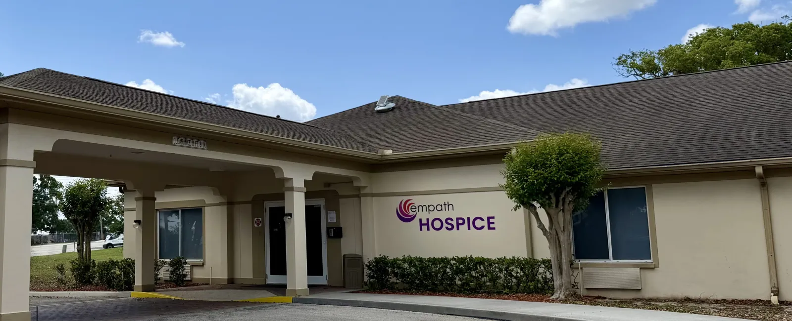 Empath Hospice building exterior with entrance driveway under blue sky and some clouds