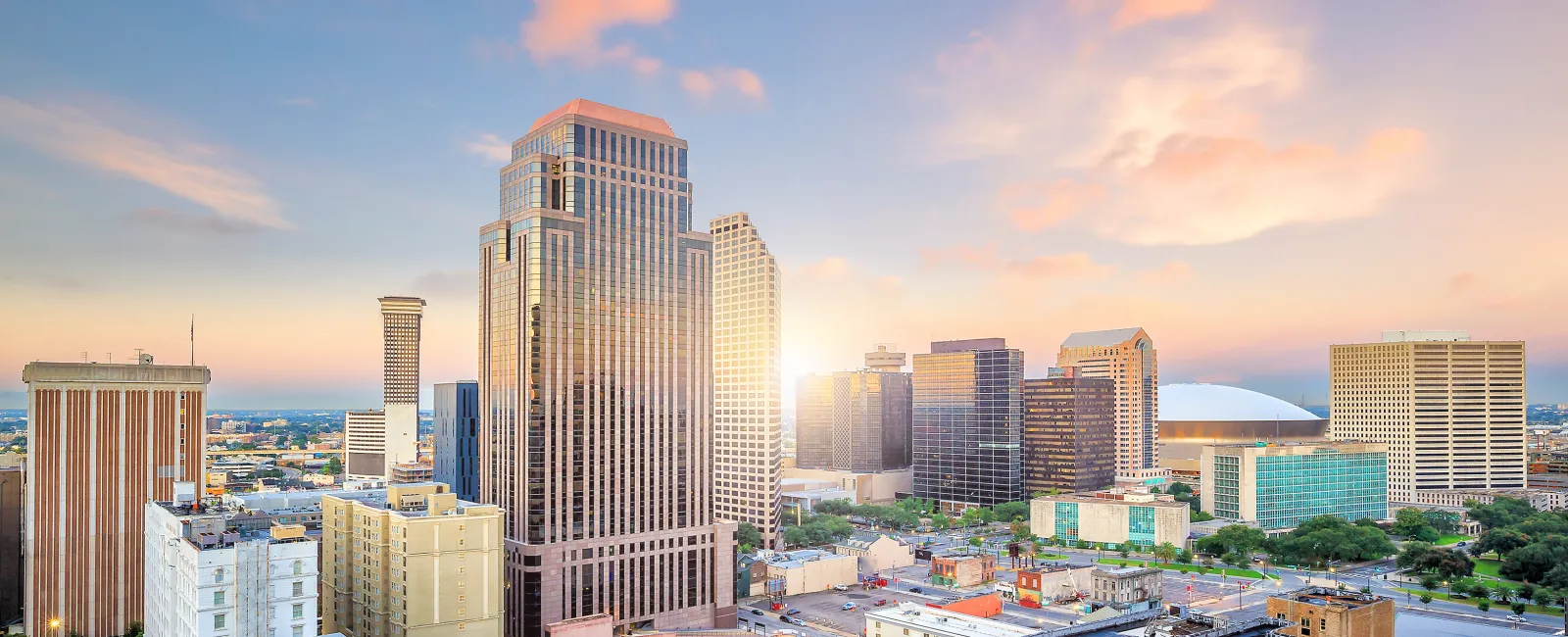 Sunset over a modern city skyline with tall buildings and vibrant colorful clouds in the sky