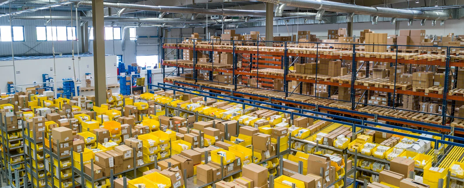 Large warehouse interior filled with shelves holding numerous brown and yellow packages ready for shipment or storage