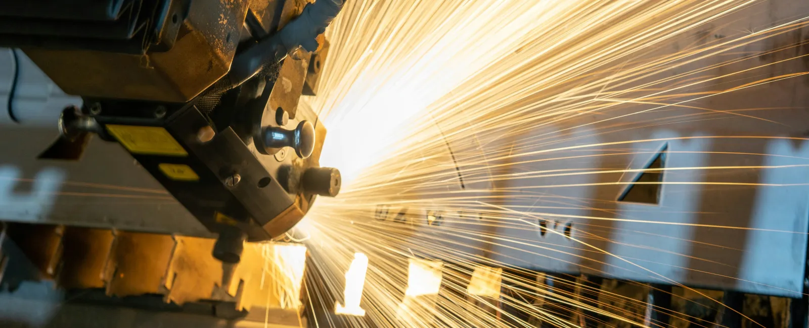 Close-up of industrial metal cutting machine producing bright sparks during operation in factory setting