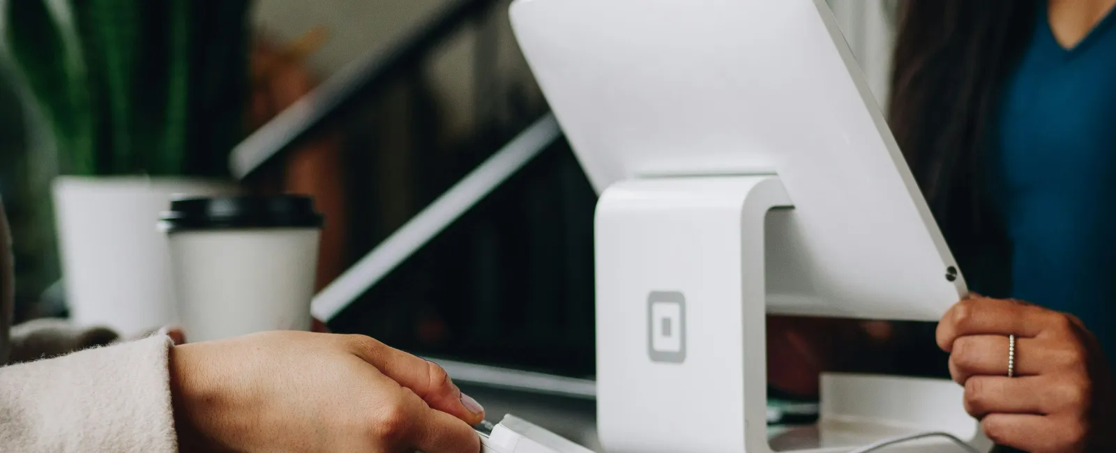 Customer making a contactless payment using card reader next to a white Square point-of-sale system