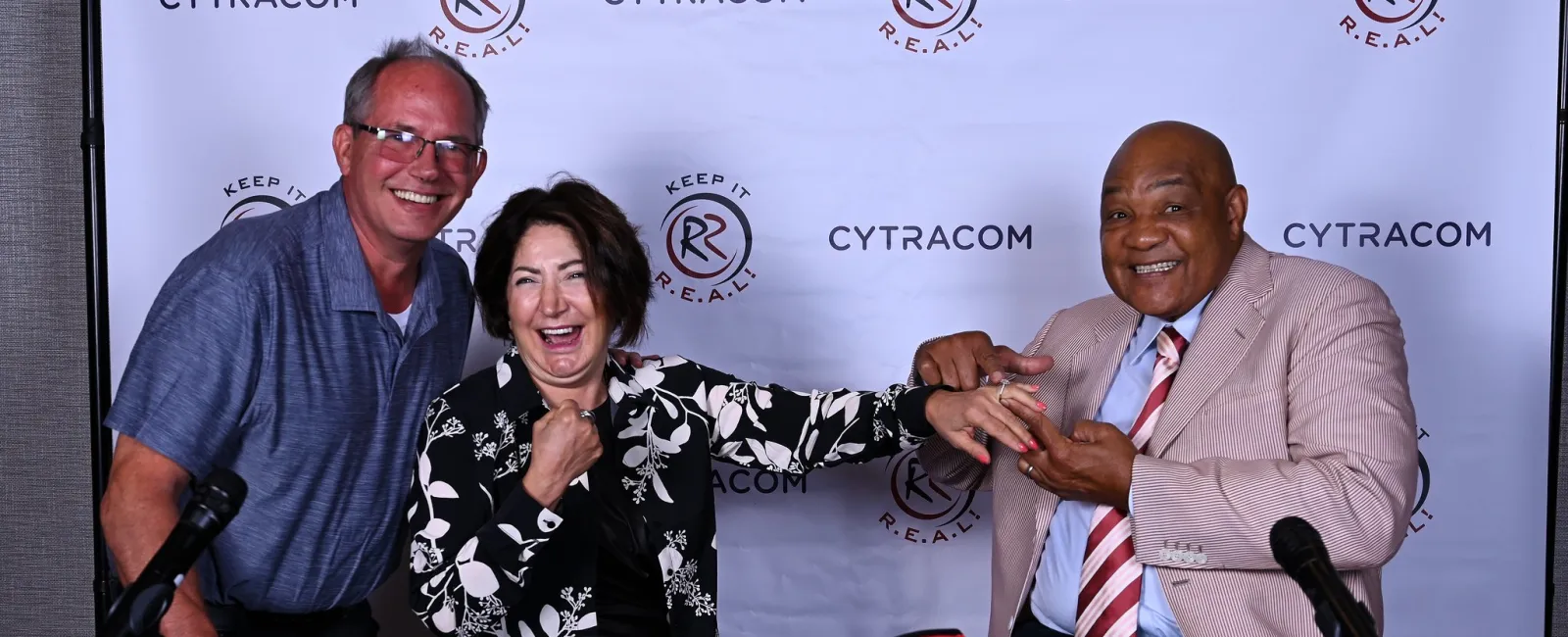 Three people smiling with signed boxing gloves, promoting Cytracom's event, Keep It R.E.A.L.
