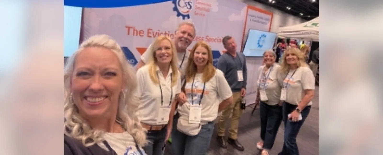 Smiling team posing at The Eviction Process Specialists booth during AAA 80s conference show.