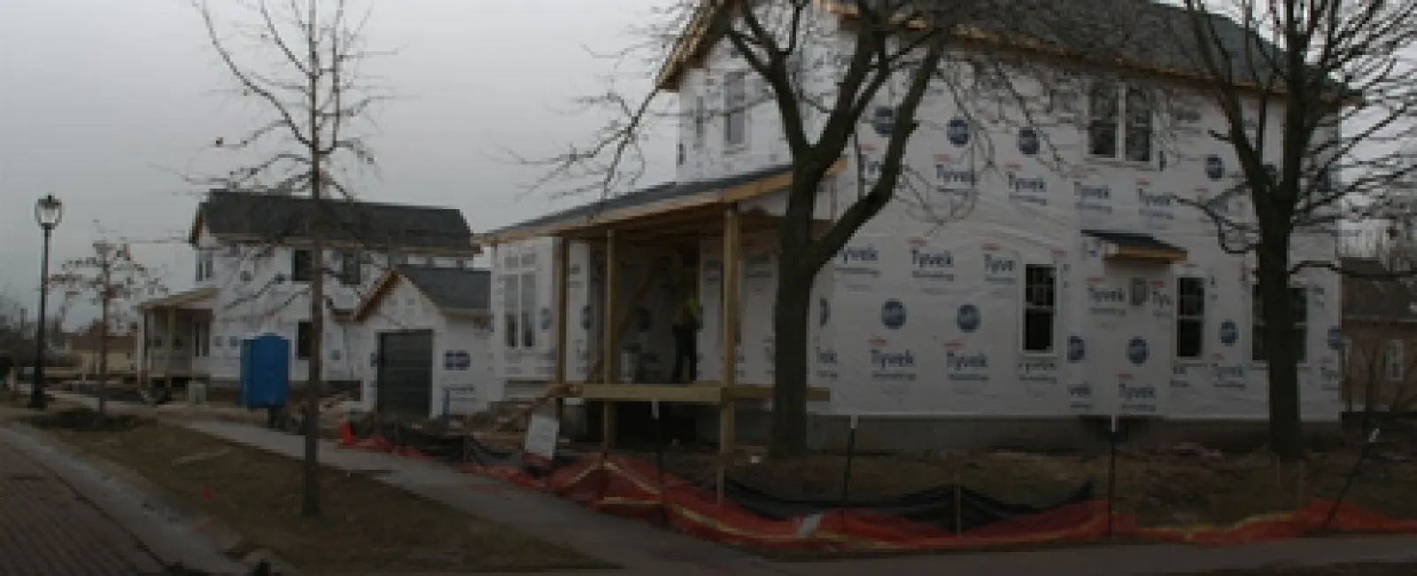 New houses under construction with Tyvek house wrap on cloudy day in residential neighborhood
