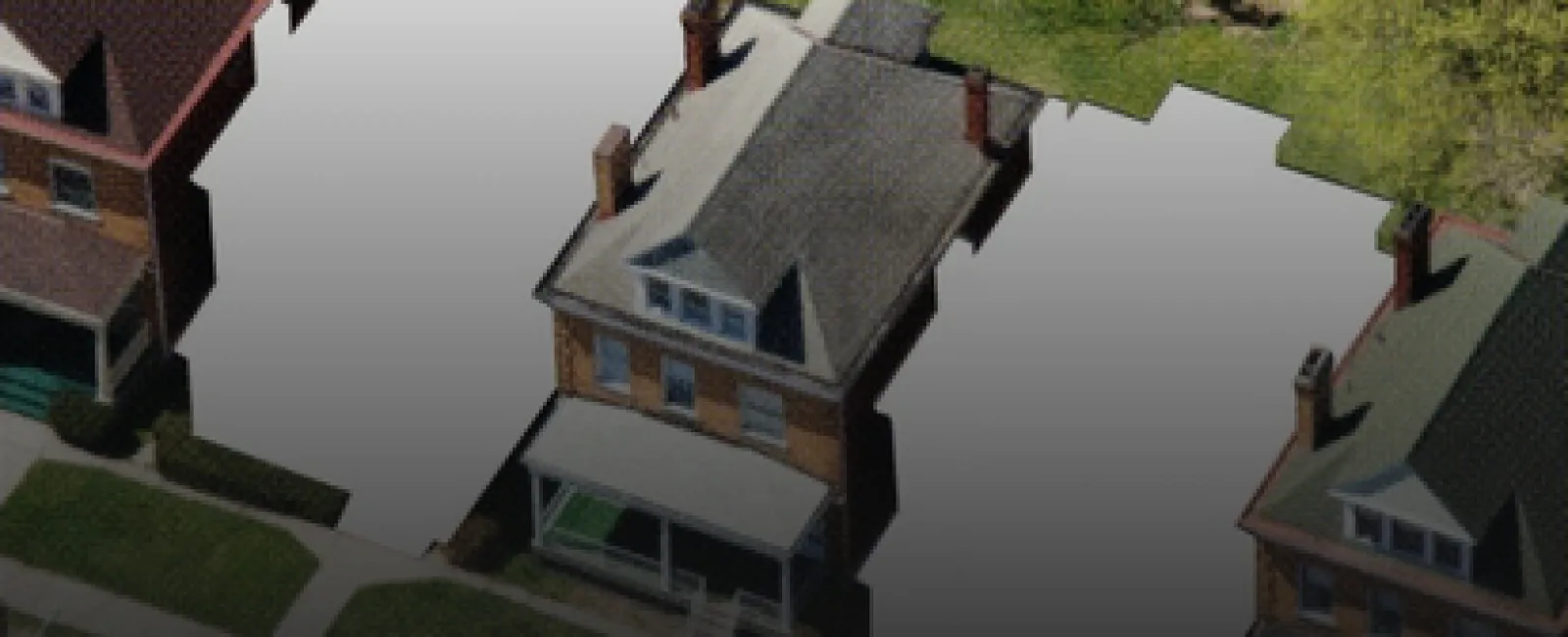 Aerial view of a neighborhood with one visible house and two vacant lots marked in white between other homes.