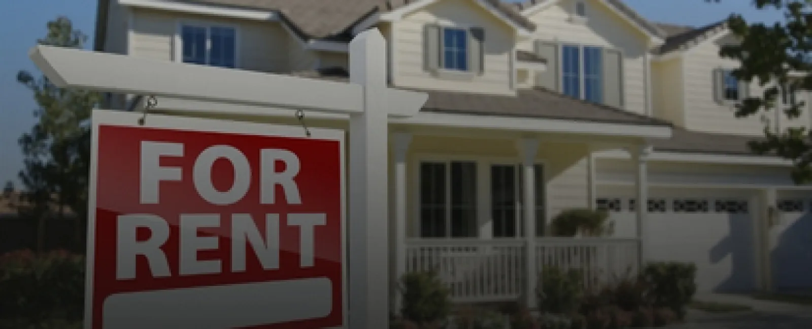 Red and white for rent sign displayed in front of a two-story suburban house with garage and porch.