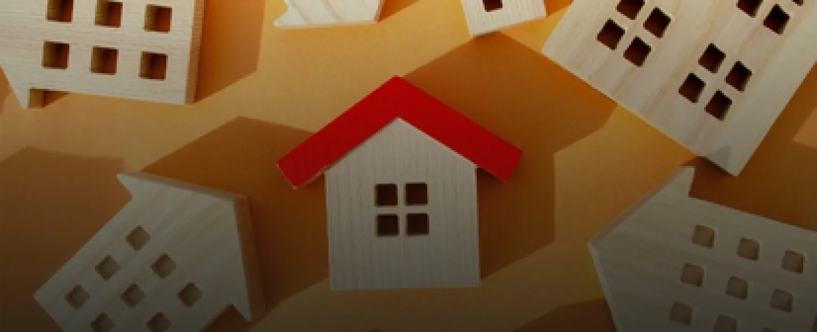 Wooden house models with one red-roofed house standing out among natural wood-colored houses