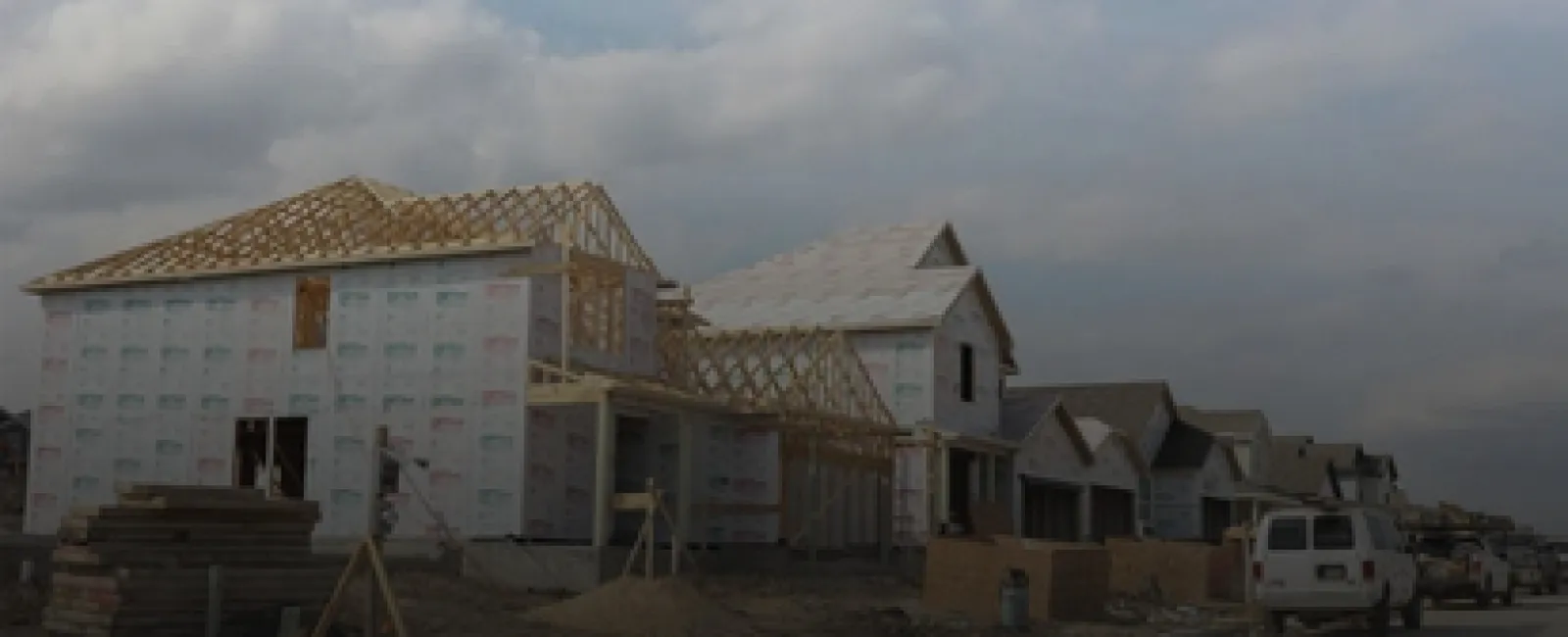New residential houses under construction in a developing neighborhood on a cloudy day.