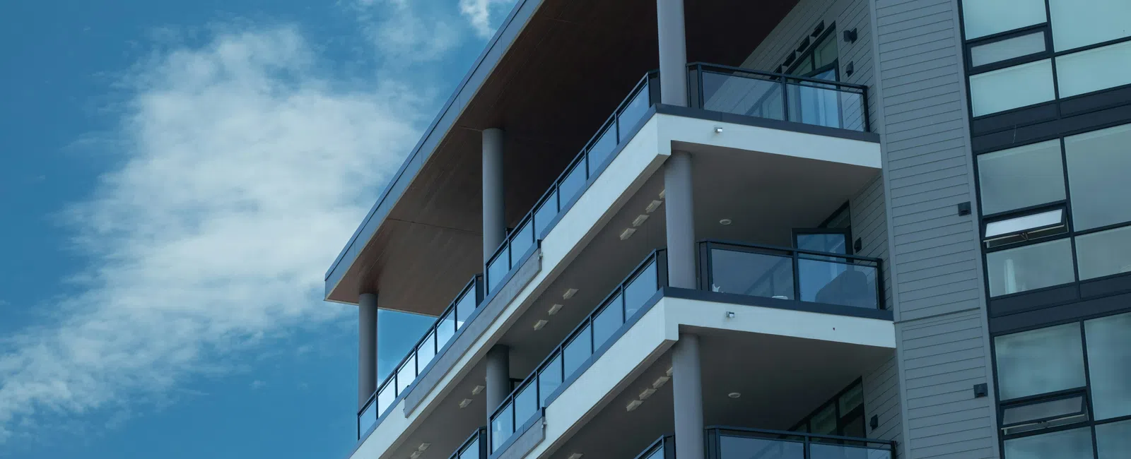 Modern apartment building with multiple balconies against a blue sky with clouds