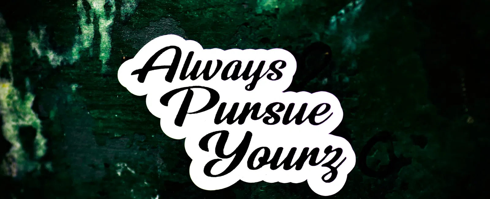 Sticker with the phrase Always Pursue Yourz in cursive font on a dark textured background.