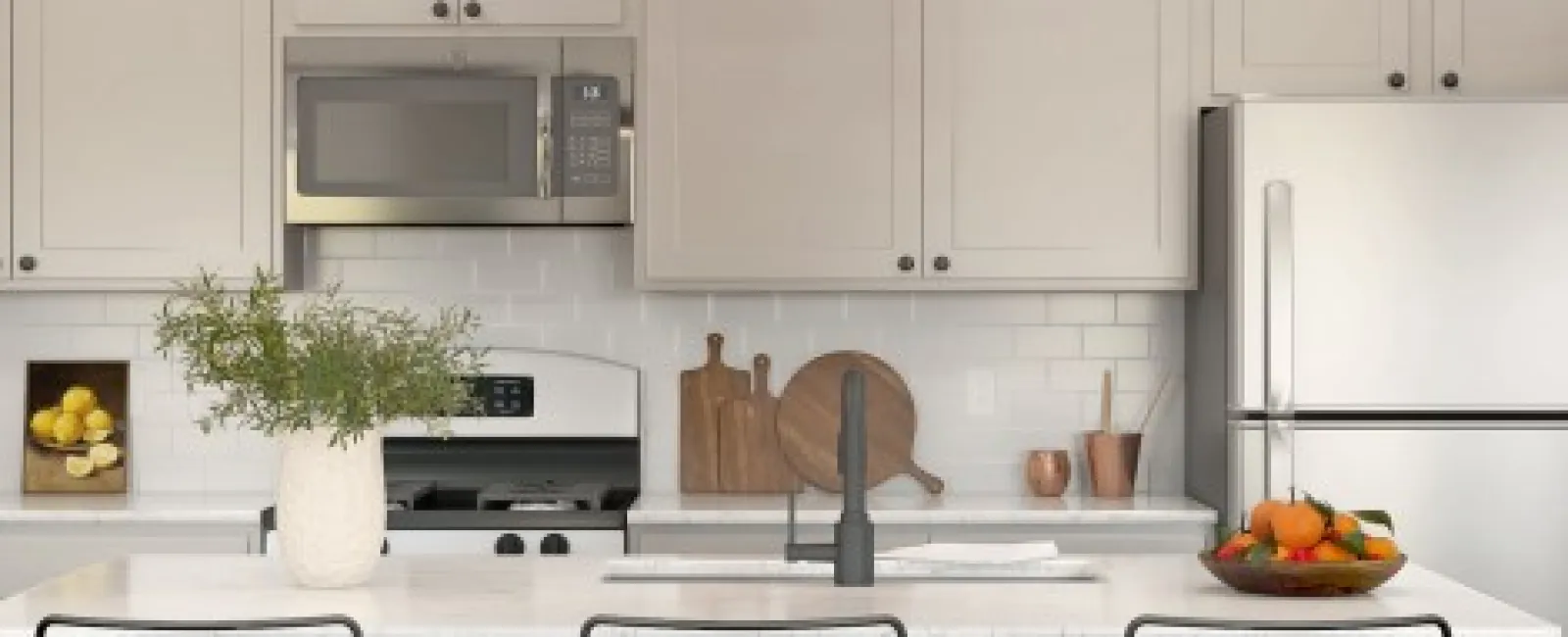 Modern white kitchen with stainless steel appliances, island seating, and decorative plants and bowls.