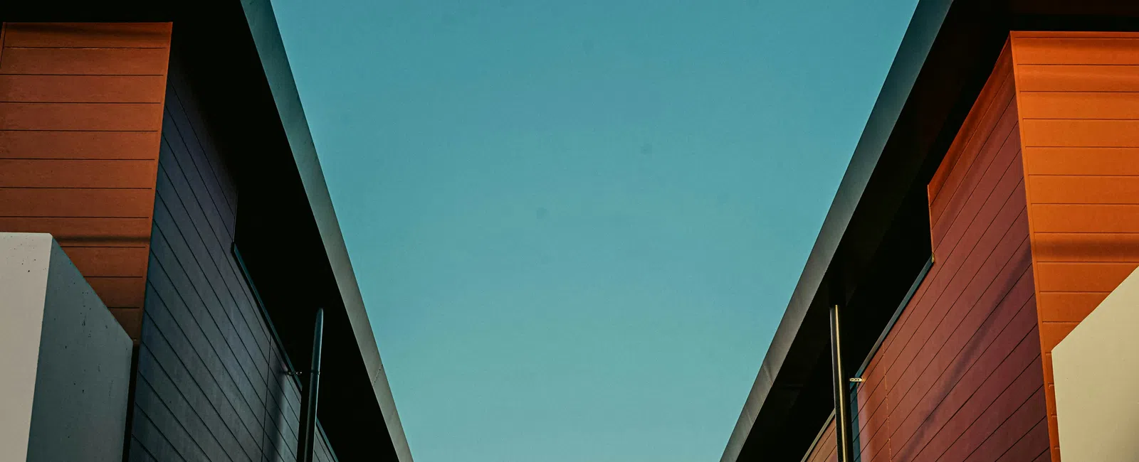 Symmetrical view of modern buildings with red and beige walls under a clear blue sky