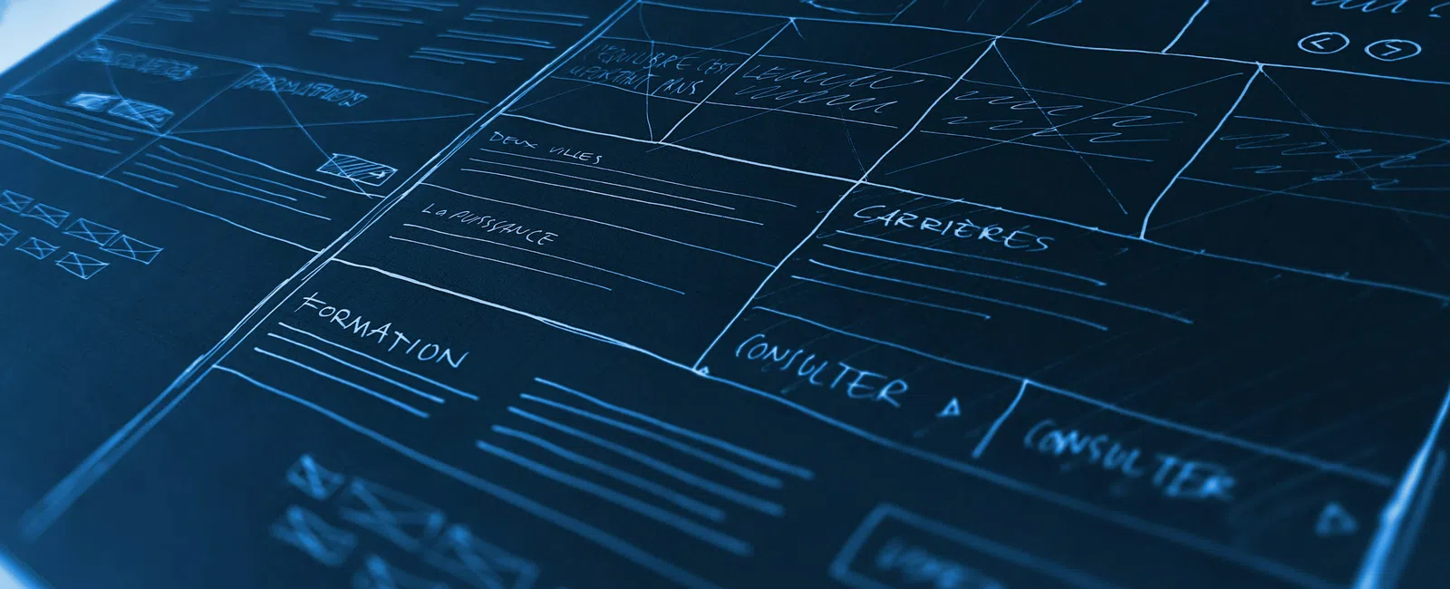 Close-up of a website wireframe sketch with sections for navigation, careers, and consulting on blue paper.