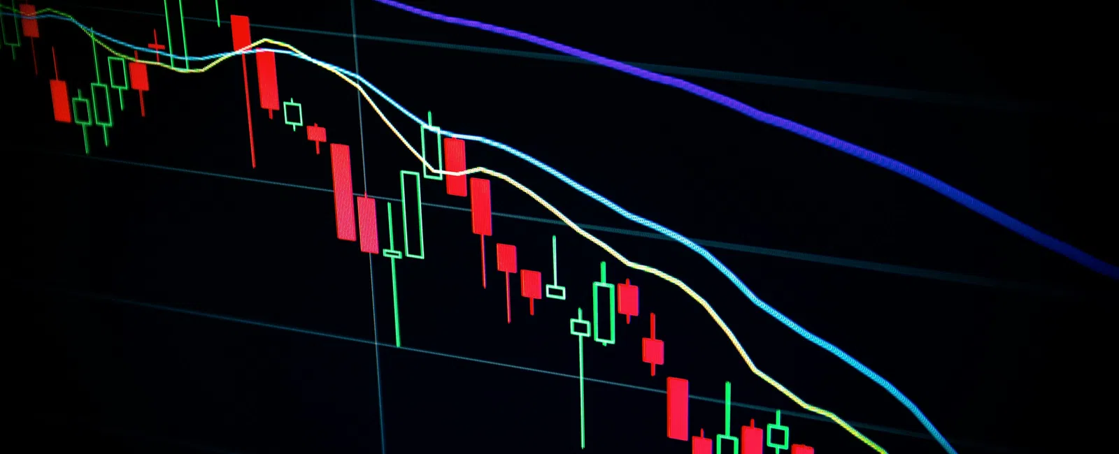 Stock market chart showing downward trend with red and green candlesticks and moving average lines on black background