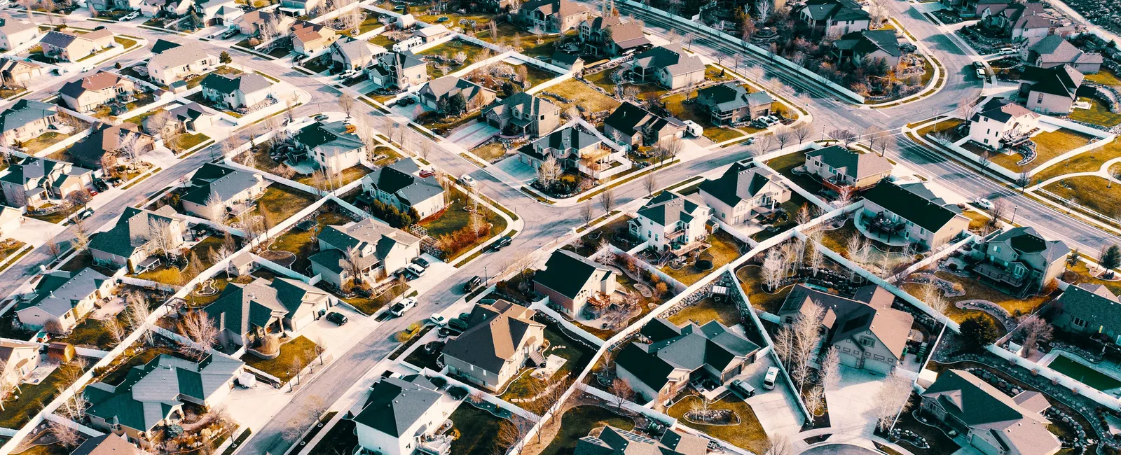 Aerial view of a suburban neighborhood with houses, streets, and lawns in a planned residential area.