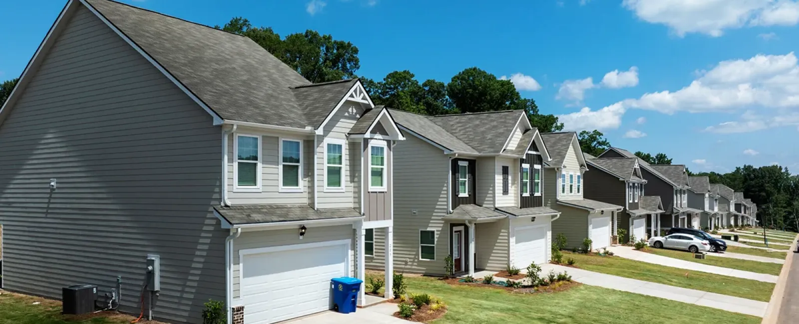 Row of modern suburban two-story houses with garages under a blue sky on a sunny day.