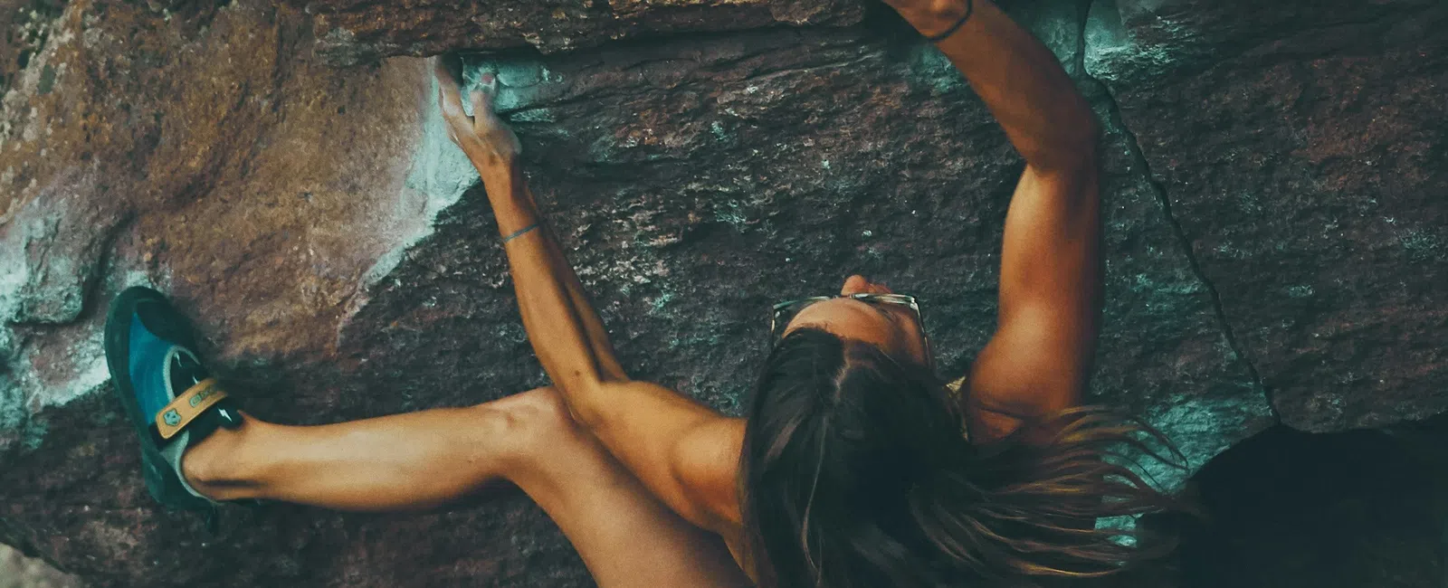 Woman rock climbing challenging overhang on rugged cliff with strong grip and focus in outdoor adventure.