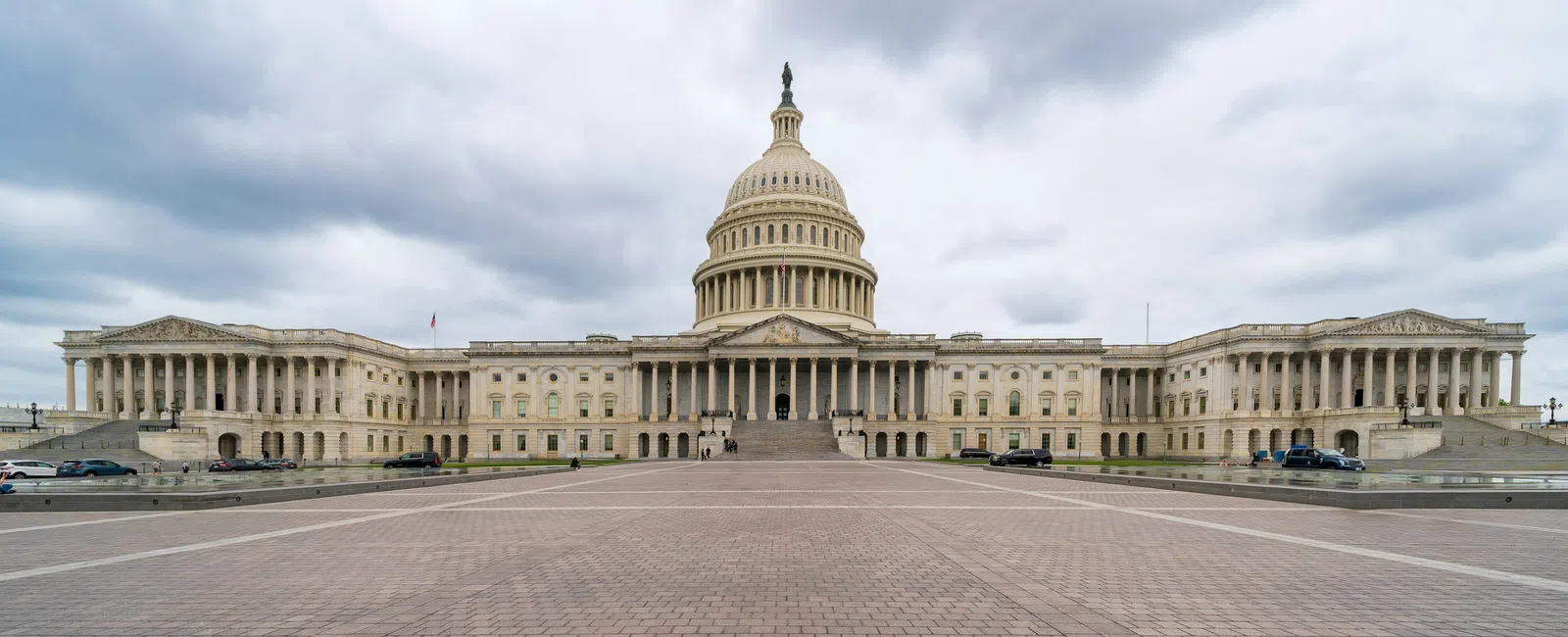 Front view of the United States Capitol building with cloudy sky and empty plaza in Washington D.C.