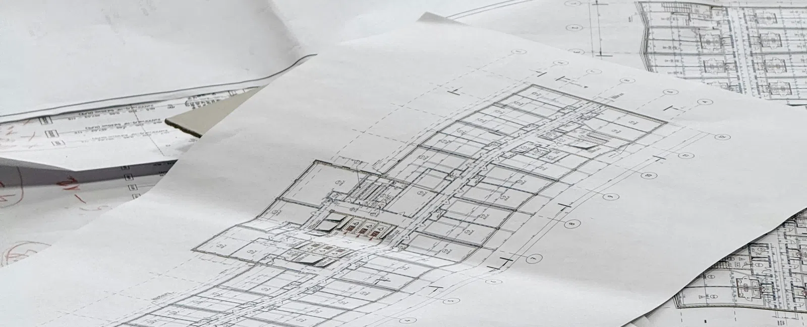 Architectural blueprints and floor plans spread out on a table showing building layouts in detail.