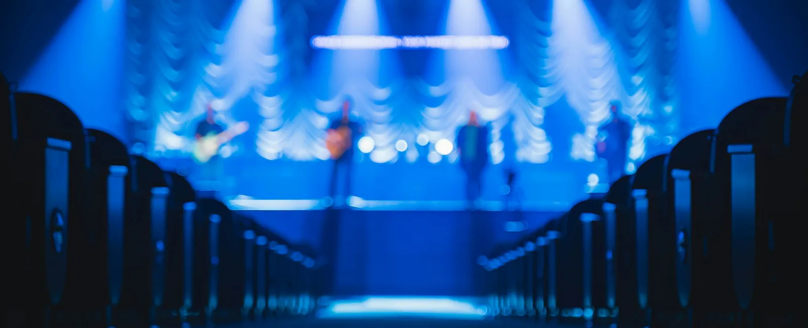 Blurry image of a stage with blue lights and performers during a live music event