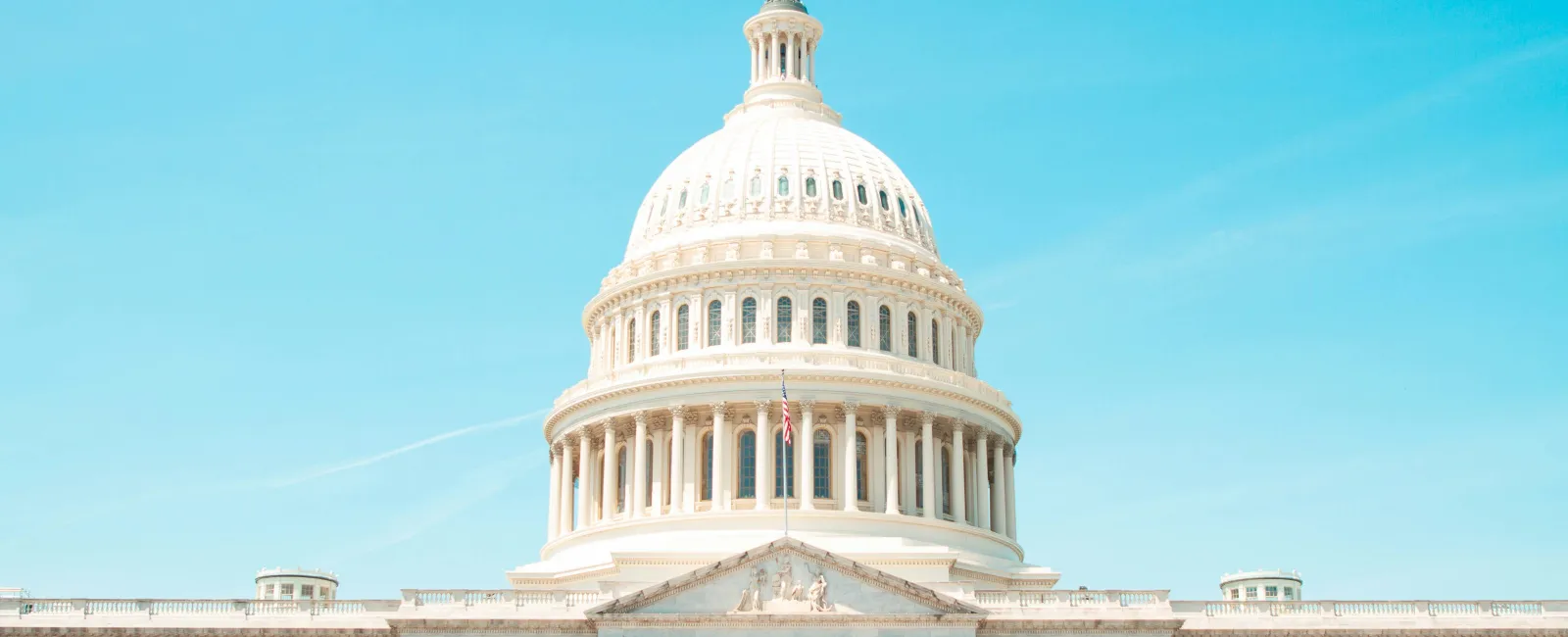 Front view of the United States Capitol building with bright blue sky in the background