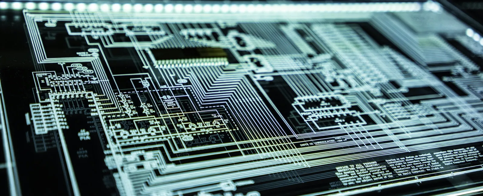 Close-up of a glowing digital circuit board with intricate wiring and technical schematic details.