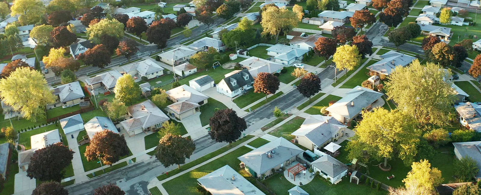 Aerial view of a suburban neighborhood with single-family homes and colorful autumn trees lining streets.