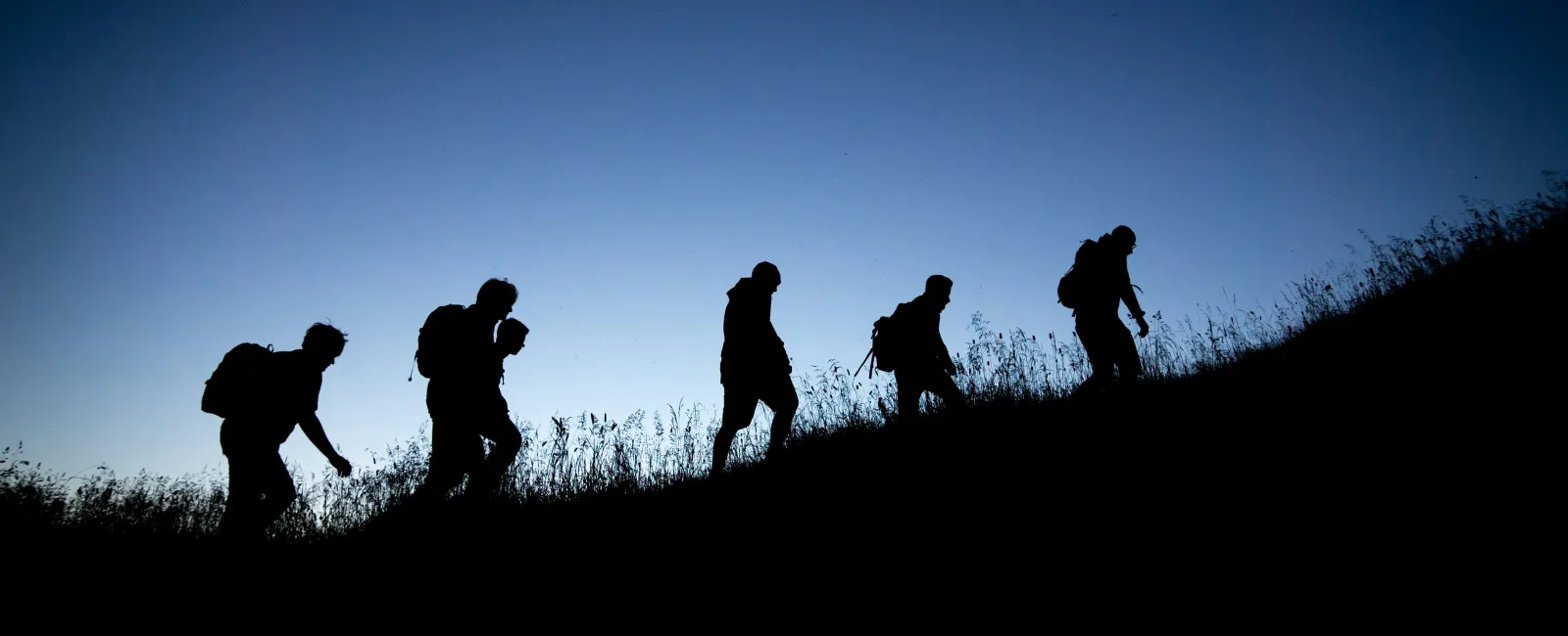 Panoramic view of a city skyline with residential areas, greenery, and mountains under a clear sky.