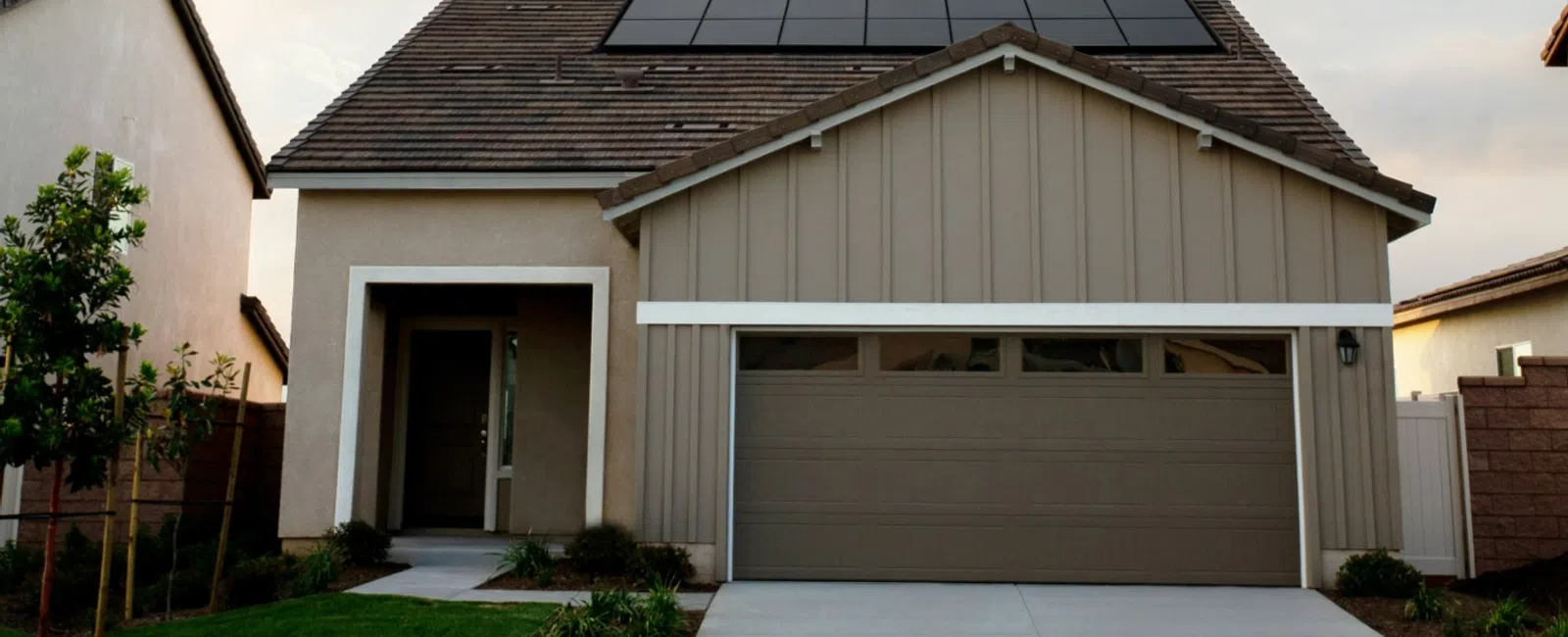Modern suburban house with solar panels on the roof and a well-maintained front yard under a clear sky.
