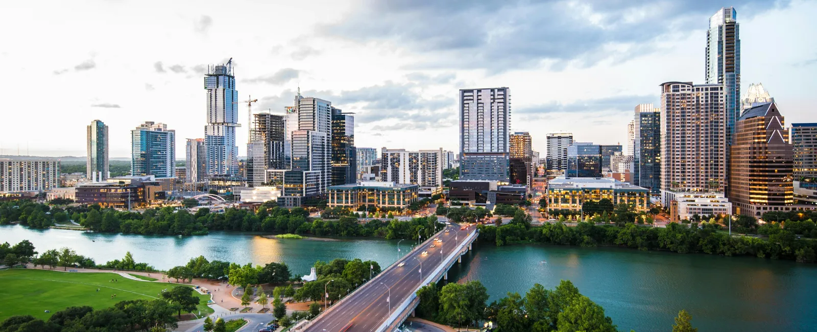 Austin city skyline with skyscrapers and Colorado River bridge at sunset under cloudy sky