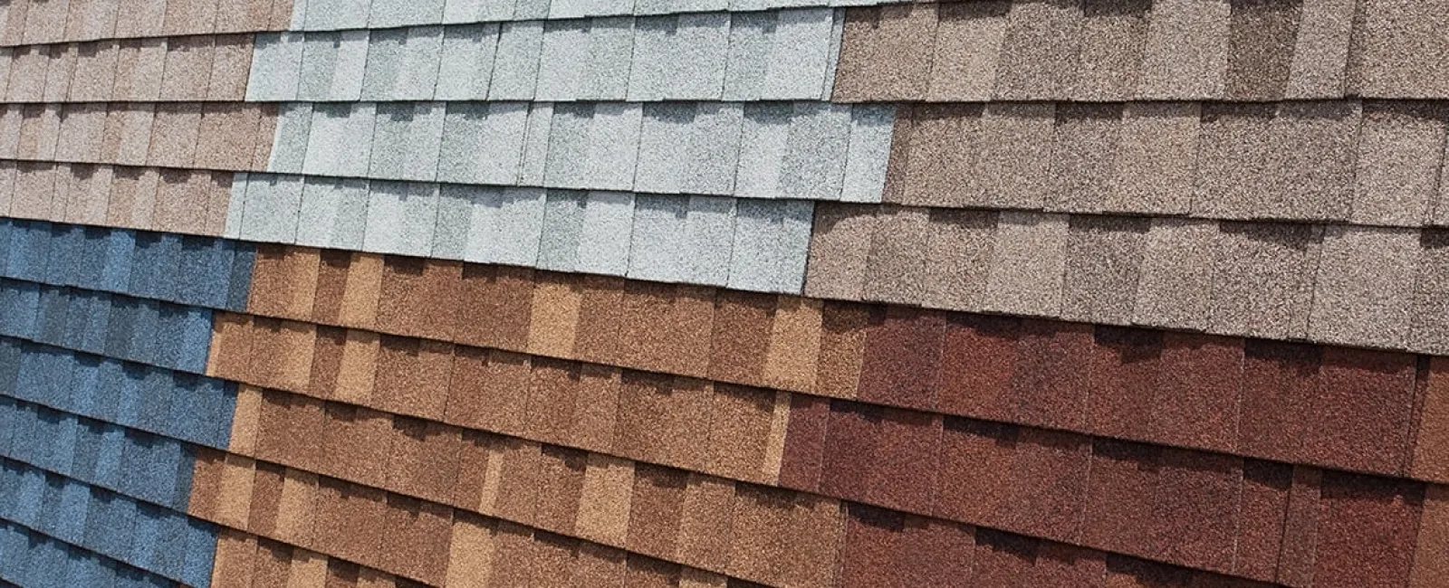 Close-up of asphalt roofing shingles in various colors including blue, gray, brown, and red arranged in rows.