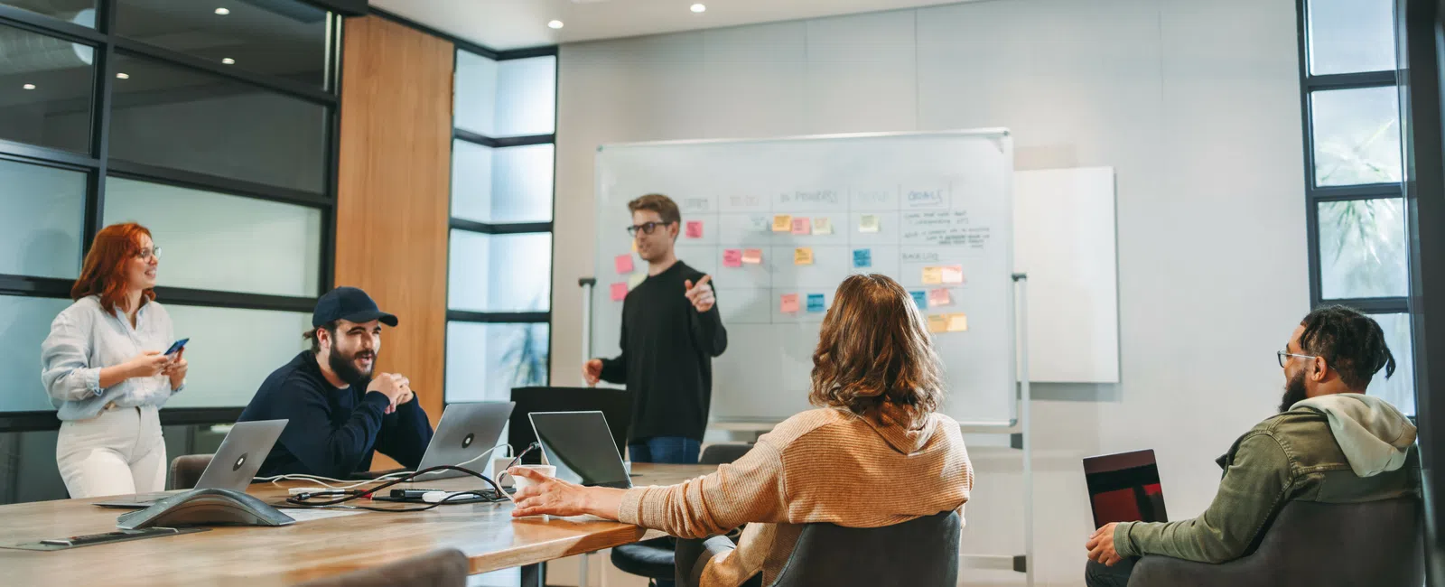 Team brainstorming session with diverse professionals discussing ideas around a conference table and whiteboard