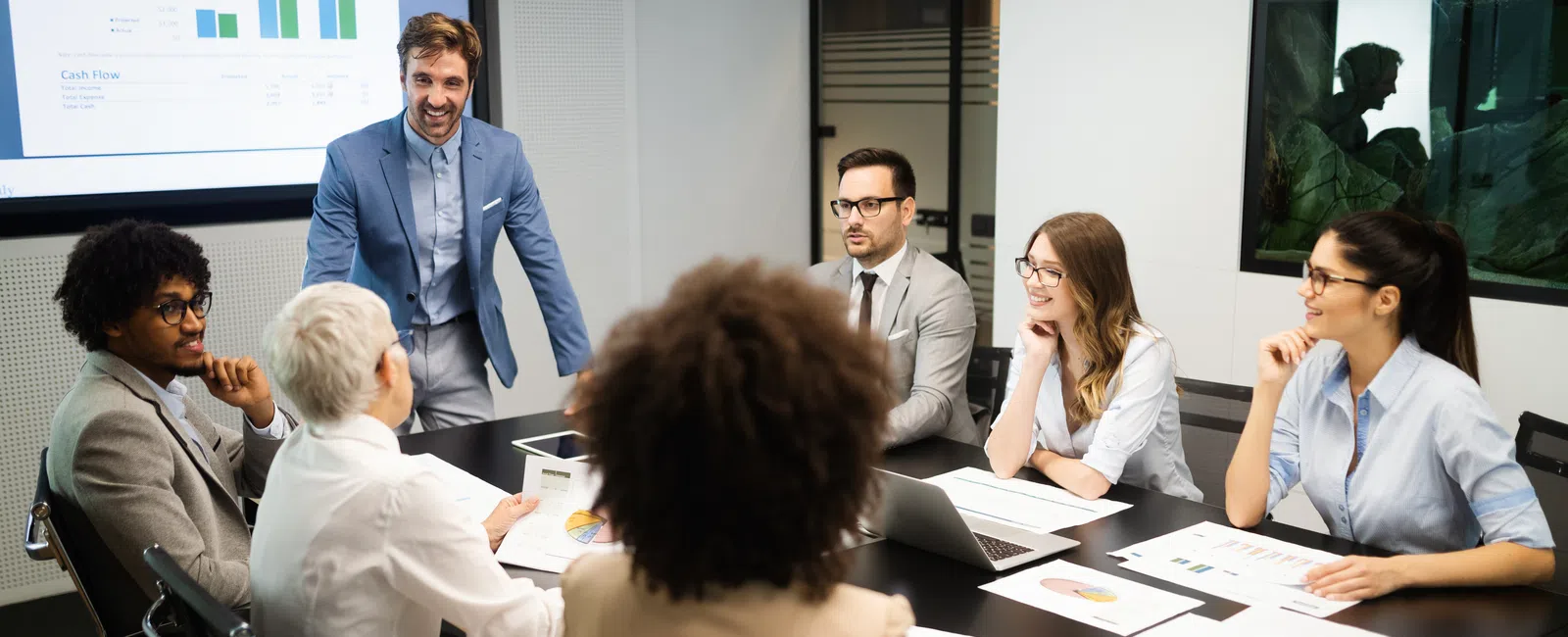 Business team in formal attire having a meeting with charts and laptop in a modern conference room