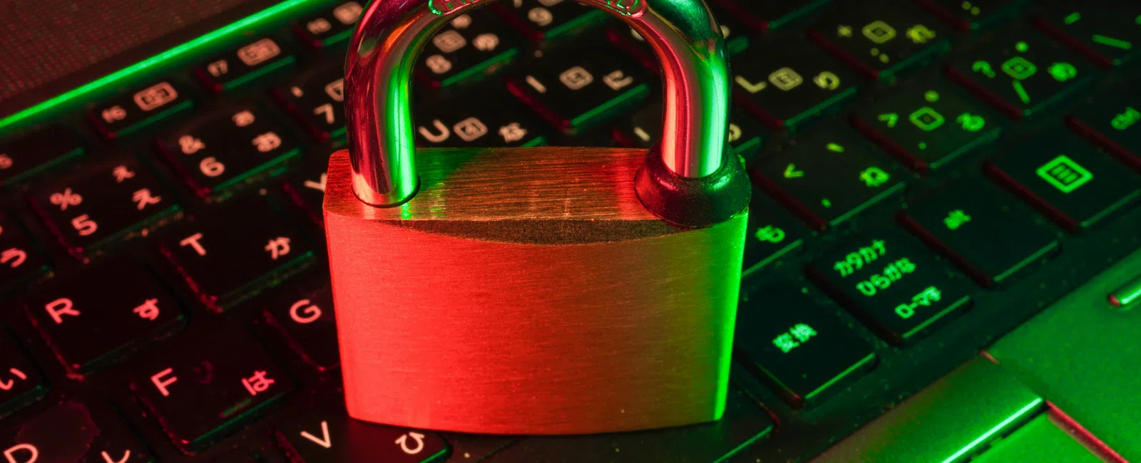 Metal padlock on black computer keyboard with green and red lighting symbolizing cybersecurity.
