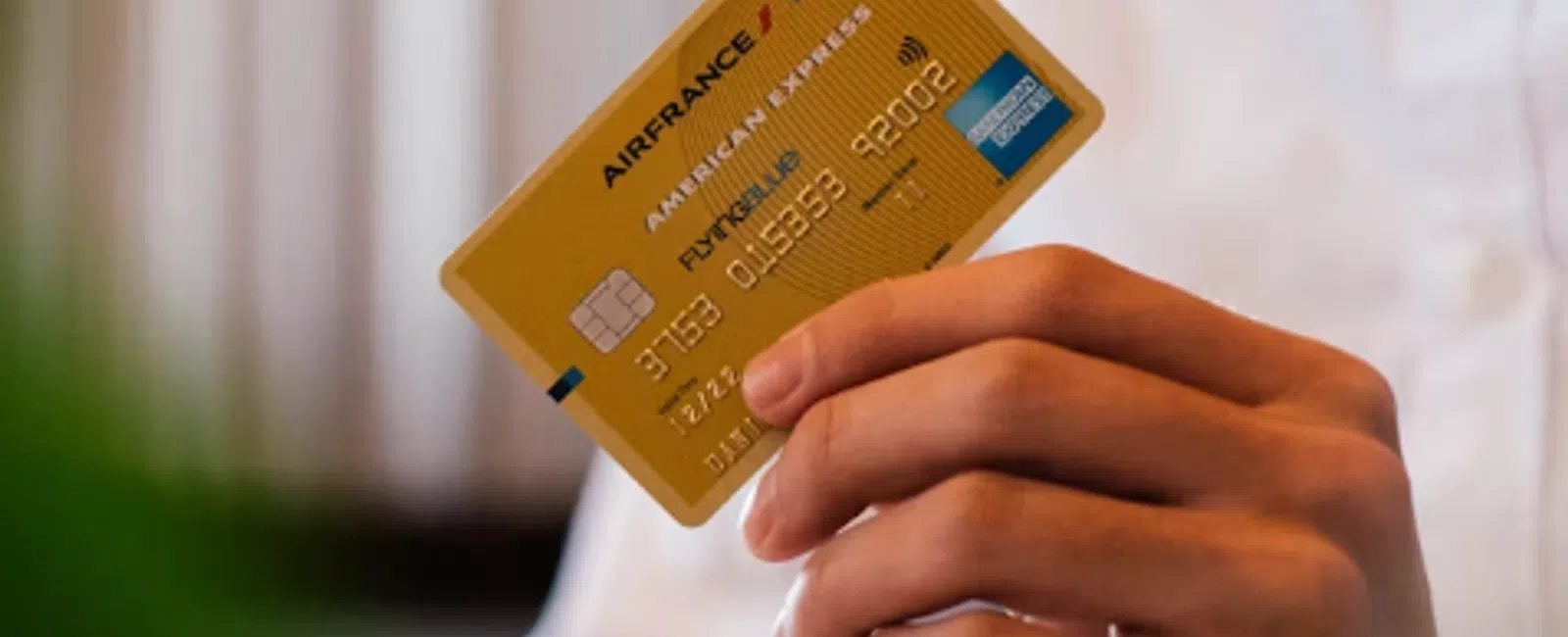 Hand holding an Air France KLM American Express gold Fly Miles credit card with blurred background