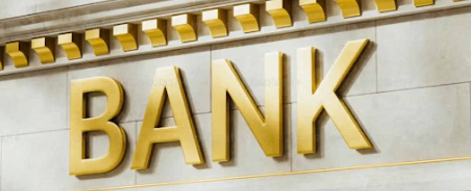 Golden letters spelling BANK on a classical stone building facade with decorative molding