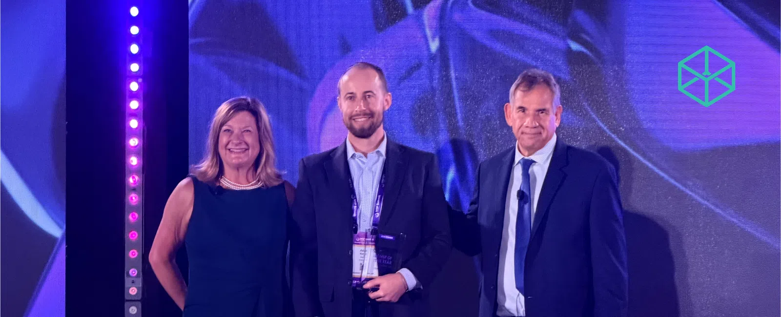Three individuals in formal attire on stage at the AI MSP of the Year 2026 award event with overlaid text.