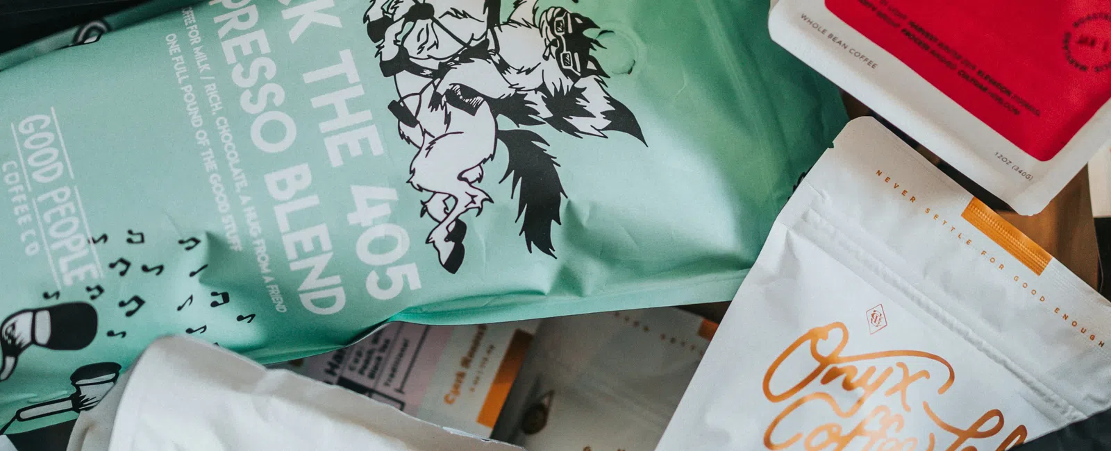 Various colorful coffee bags with distinct logos and labels arranged closely together.