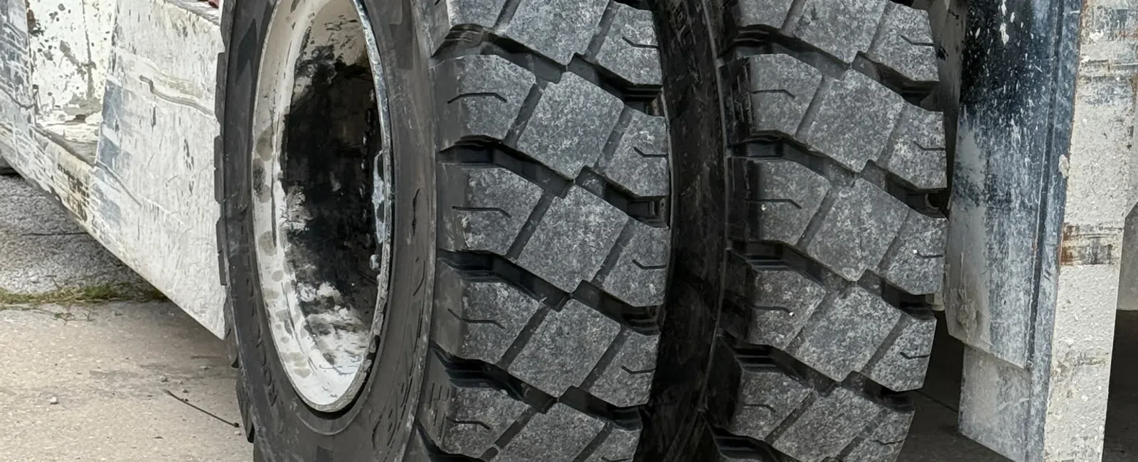 Close-up of dual heavy-duty tires on an industrial forklift with rugged tread patterns on concrete ground.
