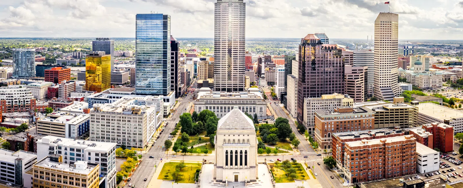 Aerial view of downtown cityscape with modern skyscrapers and historic monument at the city center under blue sky.