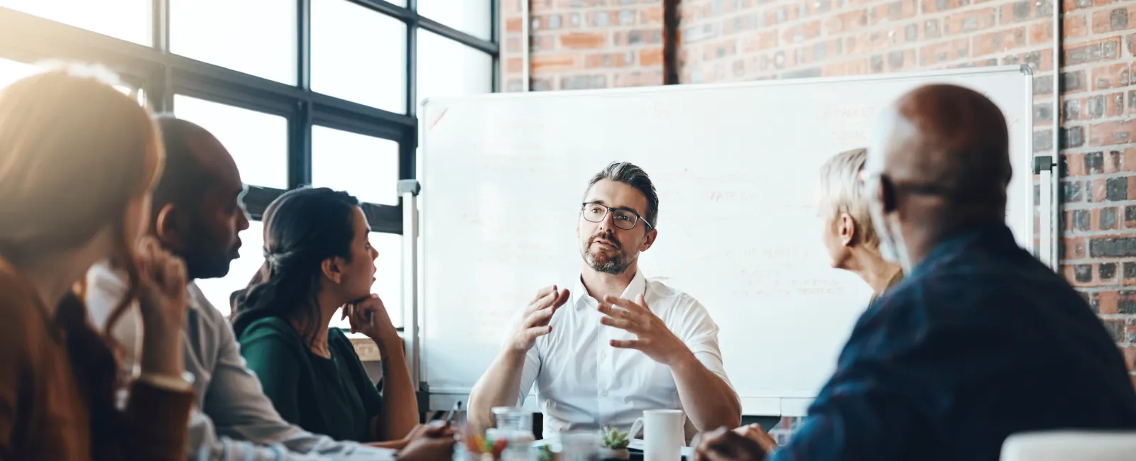 Diverse business team engaged in a discussion around a conference table in a modern office setting.
