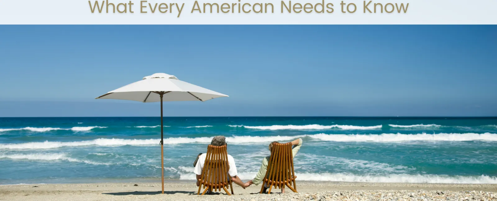 Elderly couple holding hands while sitting on beach chairs under umbrella facing ocean waves on sunny day.