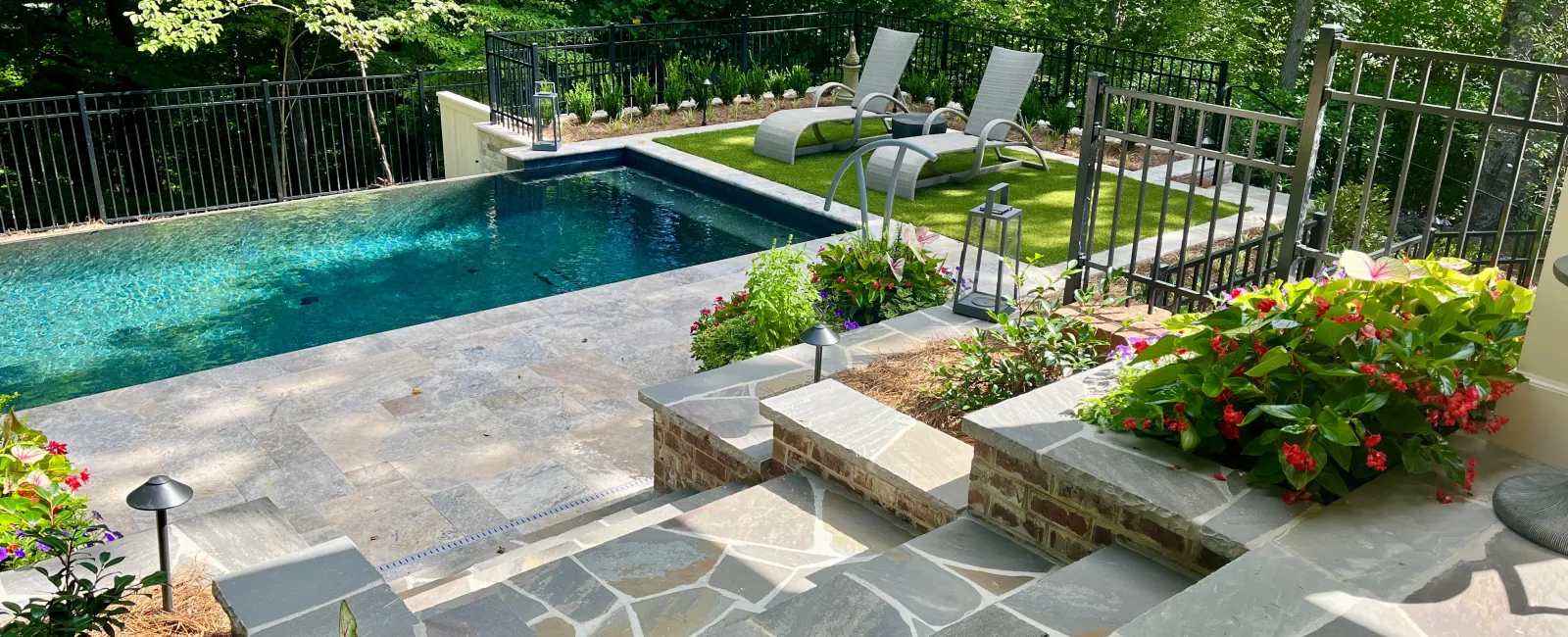 a swimming pool with hardscape and flowers