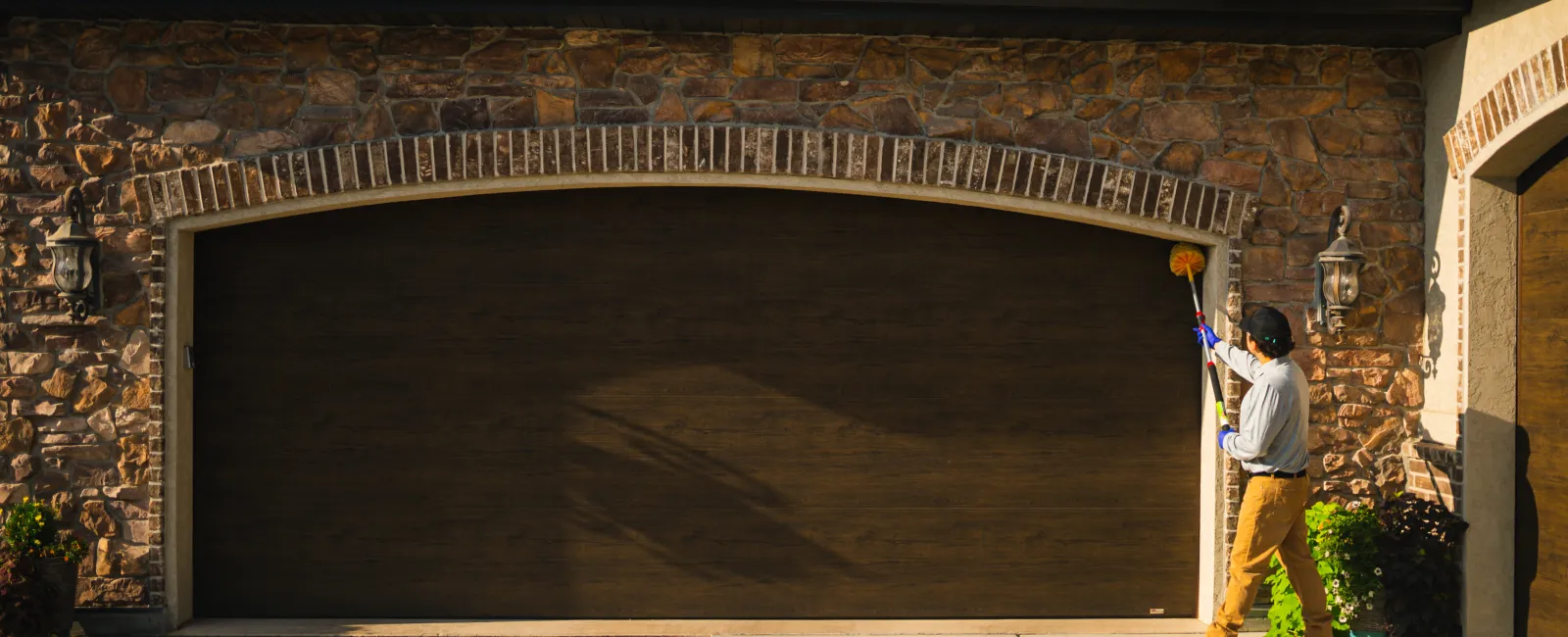 Pest control technician sweeping for spider webs to remove any existing cobwebs and spiders.