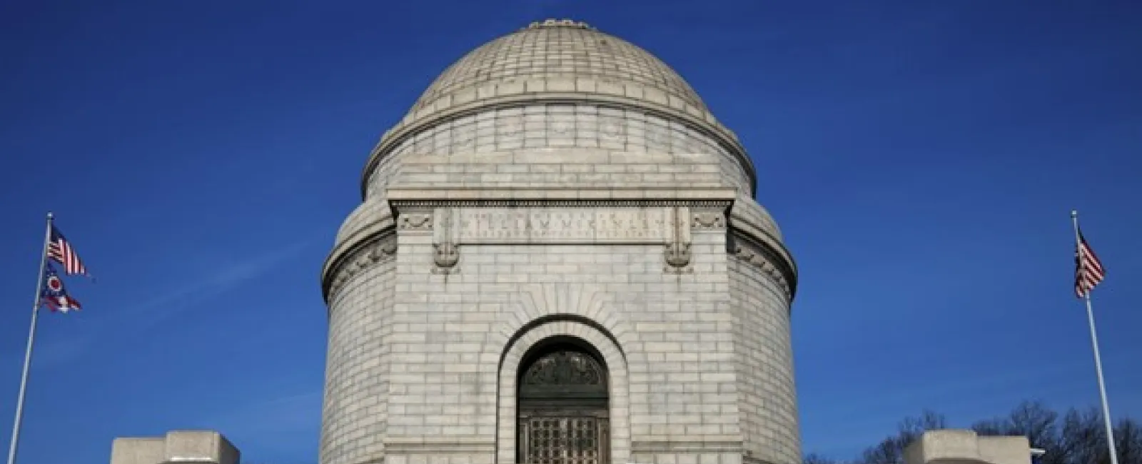 a stone building with a dome and flags on the top with McKinley National Memorial in the background