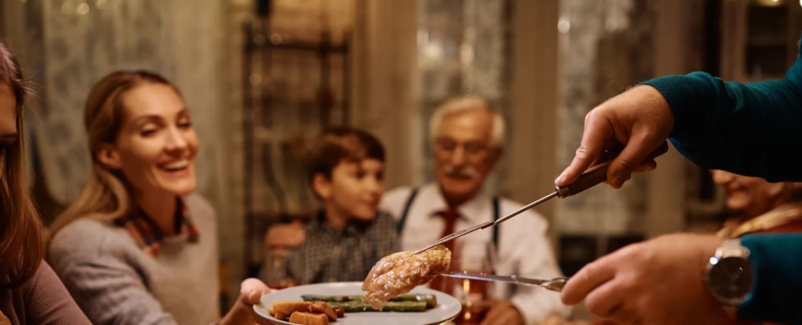Family enjoying a festive meal with roasted turkey, serving green beans and mashed potatoes together at the dinner table.
