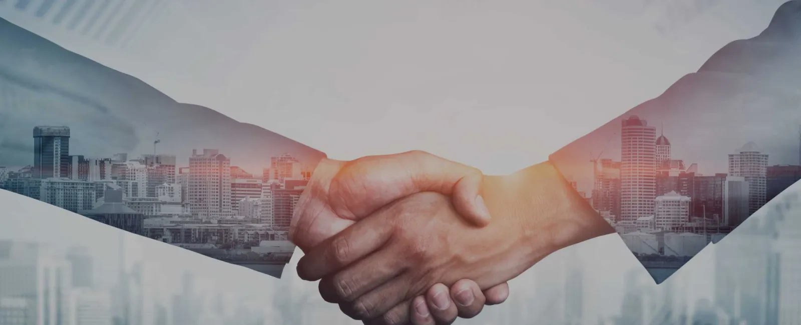 Two business people shaking hands with city skyline overlay symbolizing partnership and cooperation.